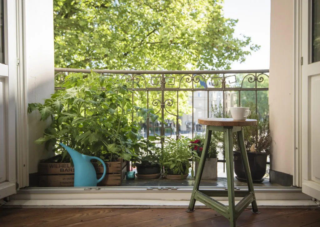 Klassische Loggia mit Säulen und Blumenschmuck an einem Wohnhaus mit rotem Ziegeldach und hellem Putz.