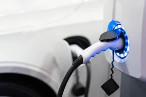 Eine E-Ladesäule, die durch blaues Licht signalisiert, dass sie gerade ein Auto auflädt.