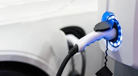 Eine E-Ladesäule, die durch blaues Licht signalisiert, dass sie gerade ein Auto auflädt.