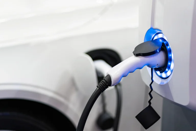 Eine E-Ladesäule, die durch blaues Licht signalisiert, dass sie gerade ein Auto auflädt.