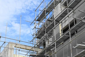 Ein Baugerüst an einer grauen unverputzten Außenfassade eines Neubaus.