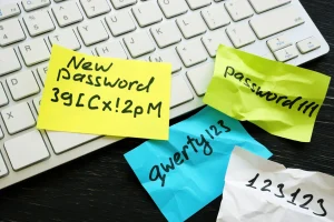 Zerknüllte Post It's liegen verstreut über eine Computertastatur, darauf sind Passwörter zu erkennen.