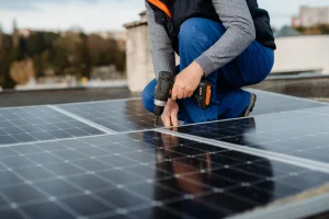 Person installiert Solarmodule auf einem Dach mit Akkuschrauber