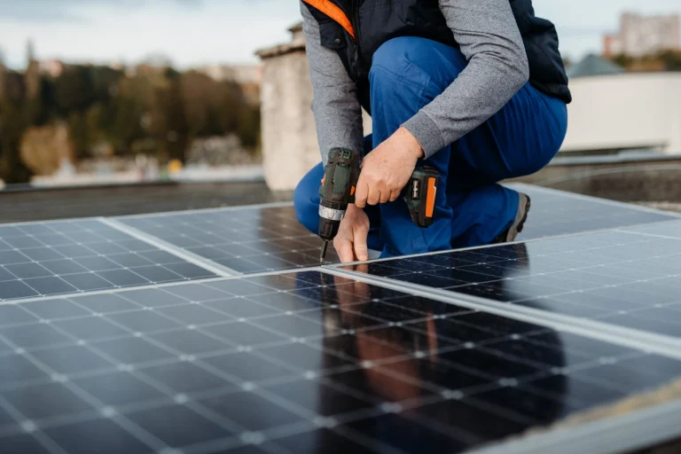 Person installiert Solarmodule auf einem Dach mit Akkuschrauber