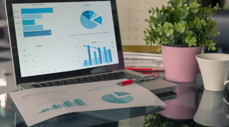 Ein Laptop steht auf einem Bürotisch, auf dem Bildschirm sind Grafiken zu aktuellen Steuern im E-Commerce zu erkennen.