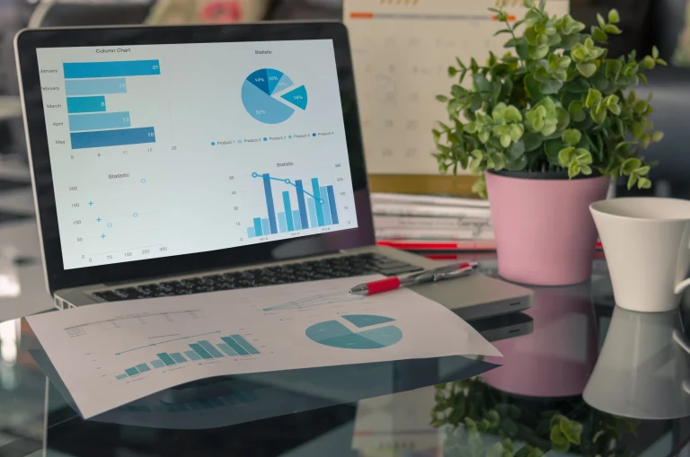Ein Laptop steht auf einem Bürotisch, auf dem Bildschirm sind Grafiken zu aktuellen Steuern im E-Commerce zu erkennen.