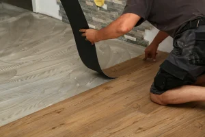 Handwerker verlegt Vinylboden in Holzoptik auf vorbereiteten Untergrund mit Kleber.