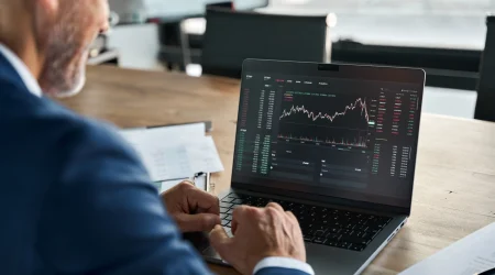 Ein Trader sitzt vor seinem Laptop und kümmert sich um die Steuern.