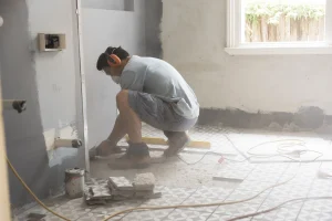 Ein Handwerker, saniert ein Badezimmer und verlegt gerade neue Fliesen.