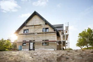 Eingerüstetes Einfamilienhaus mit grauer Fassade im Bauprozess als Beispiel für professionellen Bautenschutz.