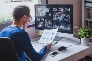 Ein Mann vor einem PC Bildschirm kontrolliert den aktuellen Cashflow seines Unternehmens.