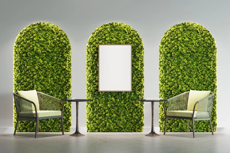 Zwei Sessel vor einer Mooswand, die in drei Rundbögen unterteilt ist.