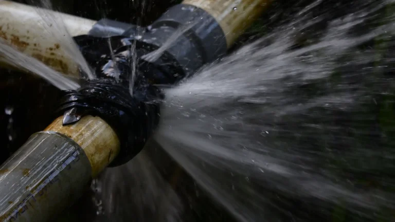 Rohrbruchortung bei einer undichten Rohrverbindung. Wasser tritt unter Druck aus dem beschädigten Anschluss aus.
