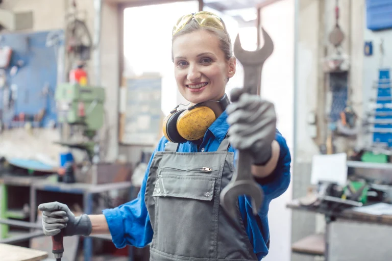 Eine Schlosserin hält einen Schraubenschlüssel in der Hand.