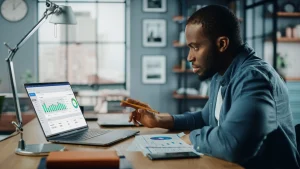 Ein Mann sitzt vor seinem Laptop und absolviert online eine Trading-Ausbildung.