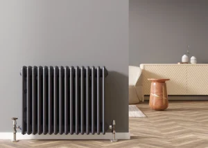 Ein Grauer Heizkörper vor einer grauen Wohnzimmerwand.