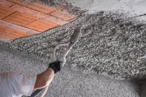 Arbeitskraft trägt Zementputz auf einer Arbeitsfläche an der Decke auf.
