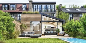 Moderner Garten mit Pool und einer gemütlichen Terrasse aus Holz. Darauf stehen ein paar Gartenmöbel in anthrazit.