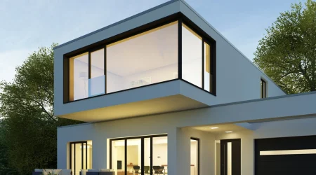 Ein modernes Haus bei Dämmerung mit einer großen Glasfront.