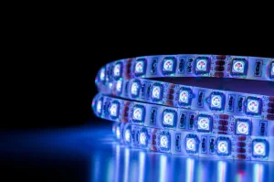 Ein blau leuchtender LED Schlauch liegt auf einer glatten Oberfläche. Der Hintergrund ist dunkel.