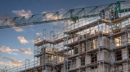 Ein Rohbau auf einer Baustelle, umzäunt von einem Baustellengerüst.