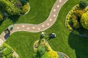 Ein neu gestalteter Garten von oben. Ein Landschaftsbauer schließt die letzten Arbeiten ab.