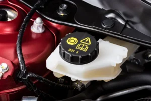 Einfüllöffnung für die Bremsflüssigkeit in einem rot lackierten Motorraum eines Autos.