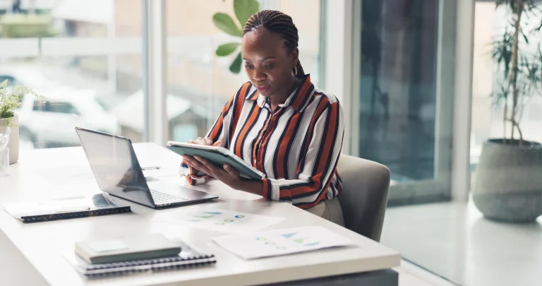 Steuerberaterin bearbeitet die Lochabrechnungen ihrer Mitarbeiter digital über ein Tablet in ihrer Hand. Sie sitzt in einer modernen Büroumgebung.