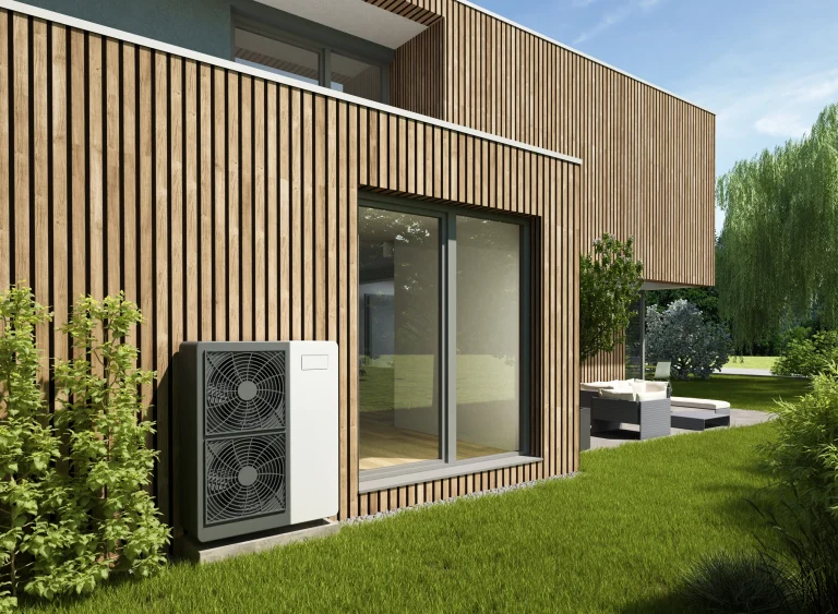 Eine moderne holzverkleidete Villa mit einer Wärmepumpe an der Hauswand im Garten.