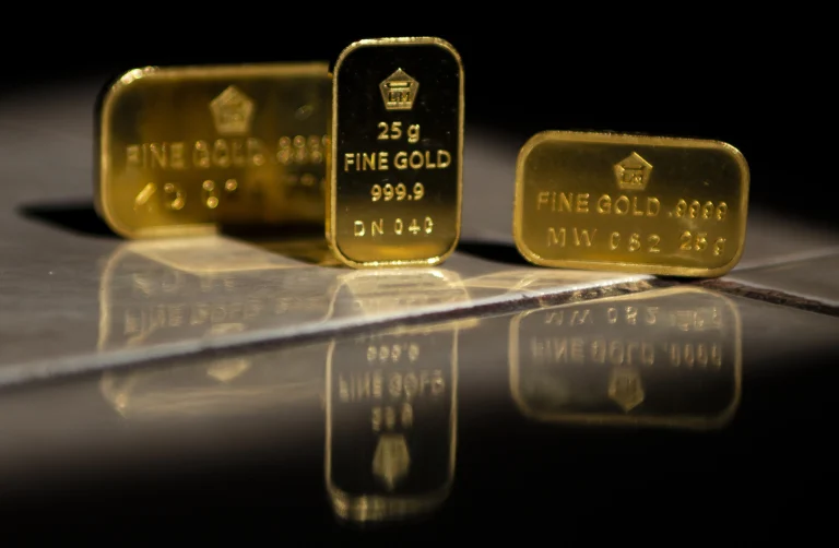 25g Goldbarren liegen auf einem glatten Untergrund in einem dunklen Raum. Nur die Barren sind beleuchtet.