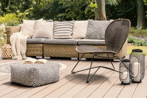 Ein Outdoor-Sofa aus Rattan auf einer Terrasse aus Holz.