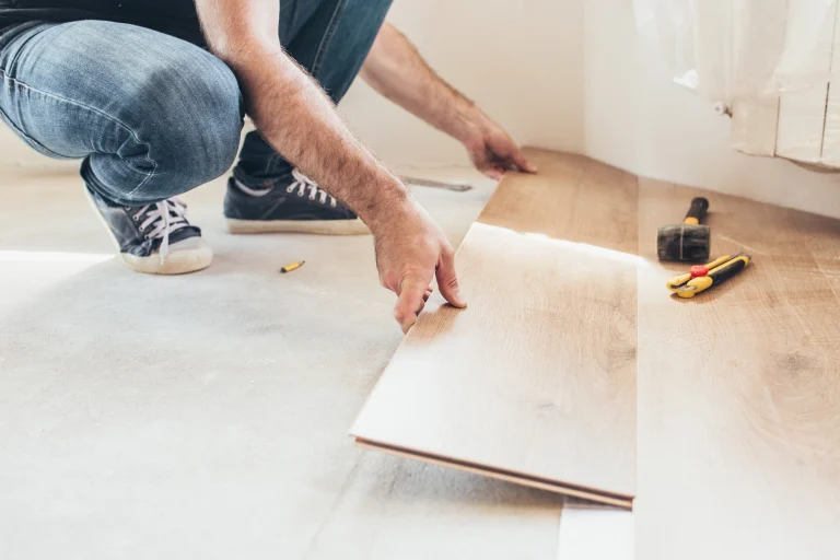 Ein Bodenleger verlegt neues Laminat in einer Wohnung.