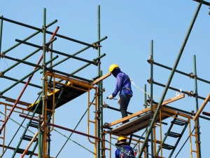 Ein Handwerker steht auf einem Gerüst einer Baustelle.