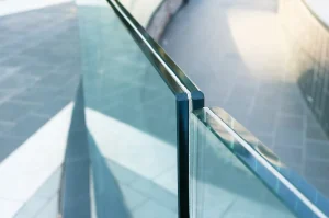 Nahaufnahme eines modernen Ganzglasgeländers aus Verbundsicherheitsglas (VSG), bei dem die zwei durch eine Folie verbundenen Glasscheiben an der Kante deutlich sichtbar sind.