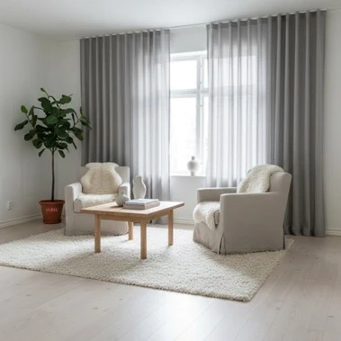 Helle Sitzecke mit zwei Sesseln. Der Raum wird leicht verdunkelt durch transparente graue Gardinen.