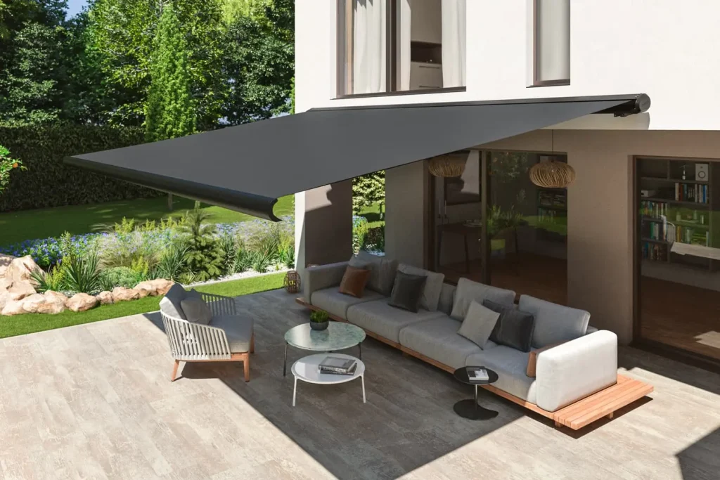 Eine ausgefahrene Vollkassettenmarkise in schwarz, über einer Terrasse mit hellen Sitzmöbeln.