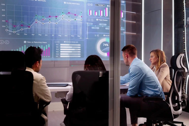 Ein Team aus Kollegen sitzt zusammen an einem Konferenztisch und bespricht die aktuellen Statistiken zum Geschäftsjahr.