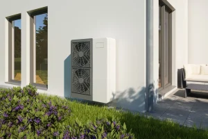 Eine Wärmepumpe an einer modernen weißen Hausfassade.