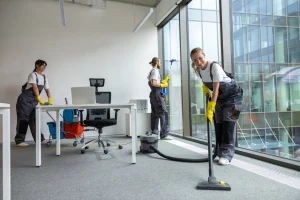 Drei Gebäudereiniger putzen ein Büro.