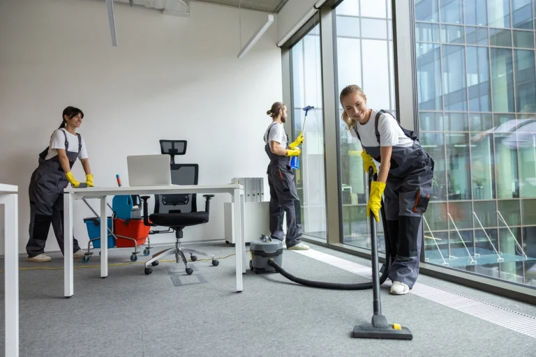 Drei Gebäudereiniger putzen ein Büro.