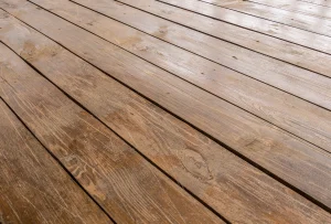 Perspektivische Ansicht einer Terrasse aus Kiefernholz. Die braun lasierten Holzdielen mit sichtbarer Maserung und Astlöchern sind parallel angeordnet und bilden einen strapazierfähigen Bodenbelag für den Außenbereich.
