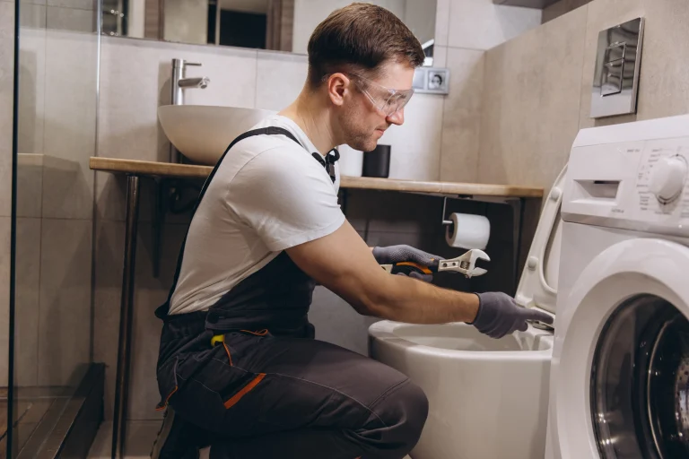 Ein Sanitärinstallateur montiert ein Klo und schließt es an das Rohrsystem, des Hauses an.