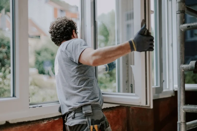Ein Handwerker der ein Fenster in den Fensterrahmen einsetzt.