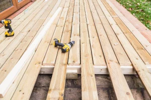 Konstruktion aus Holz für den Anbau einer Terrasse. Darauf liegt ein gelber Akkuschrauber.