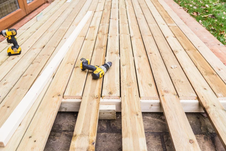 Konstruktion aus Holz für den Anbau einer Terrasse. Darauf liegt ein gelber Akkuschrauber.
