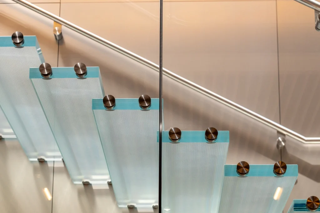Moderne Kragarmtreppe mit dunklen Stufen und einer Glaswand als Geländer.