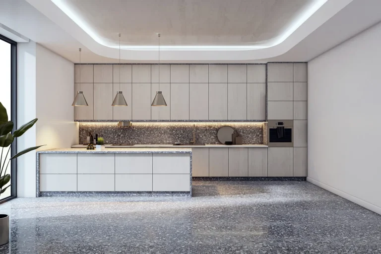 Moderne, minimalistische Küche mit einer Kochinsel und grifflosen Fronten in heller Holzoptik. Der gesamte Raum ist mit einem fugenlosen, grau melierten Terrazzoboden ausgestattet, dessen Muster sich im Fliesenspiegel der Küchenzeile widerspiegelt.
