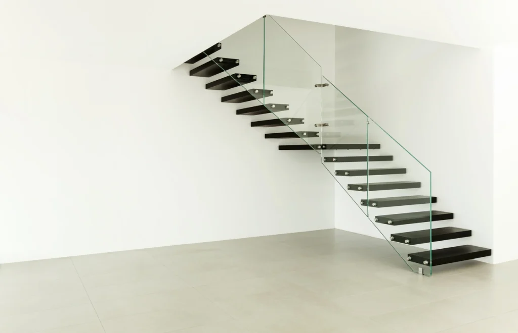 Kragarmtreppe an weißer Hauswand mit Glasgeländer.