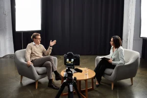 Eine Podcasterin führt in einer gemütlichen Umgebung ein Interview mit einem Finanzexperten.