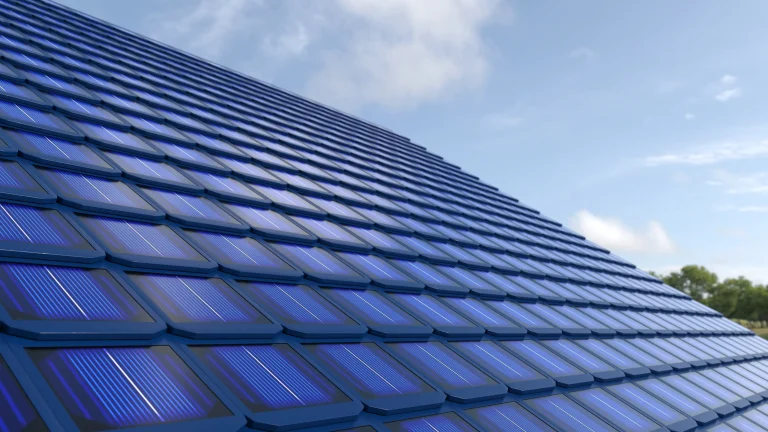 Schrägansicht eines Hausdachs, das flächendeckend mit blauen Solardachziegeln zur Photovoltaik-Stromerzeugung gedeckt ist.